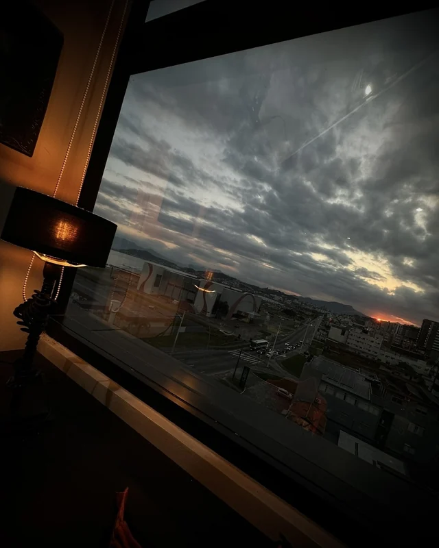 Janela do estúdio com a vista da cidade e do mar ao entardecer